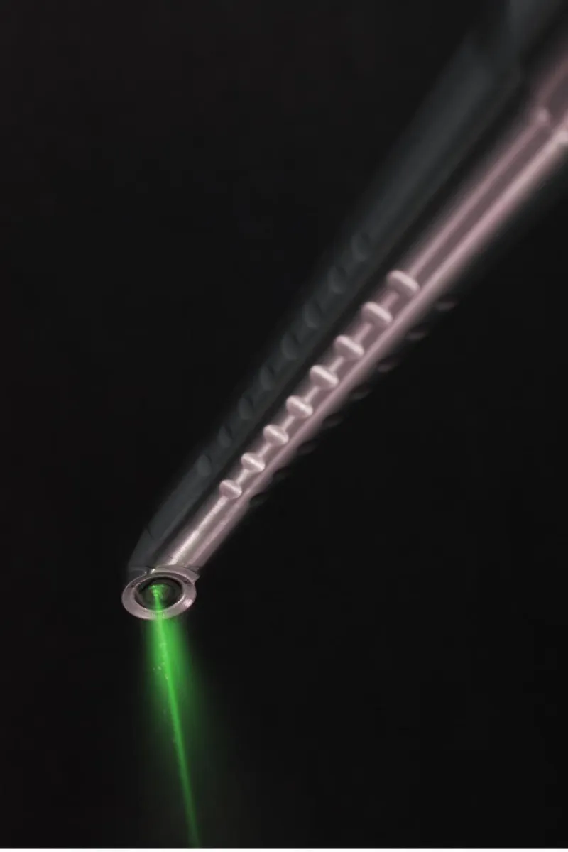 A dental laser handpiece in a darkened room