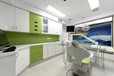 A calm treatment room at a Magical Smiles clinic, with a window mural of a beach to help children relax in the chair