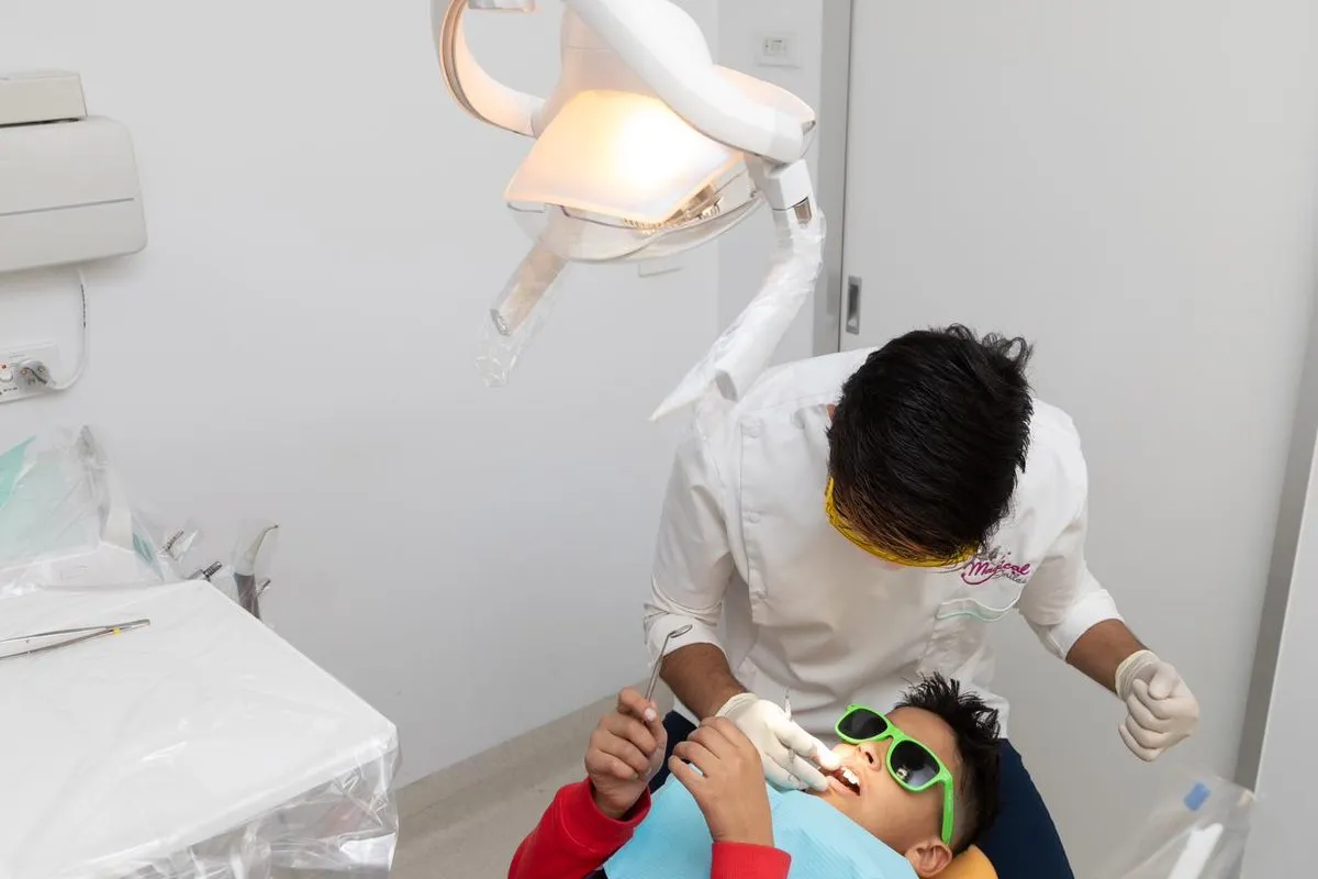 A young child in green sunglasses relaxing in the dental chair during a check-up with a Magical Smiles dentist.