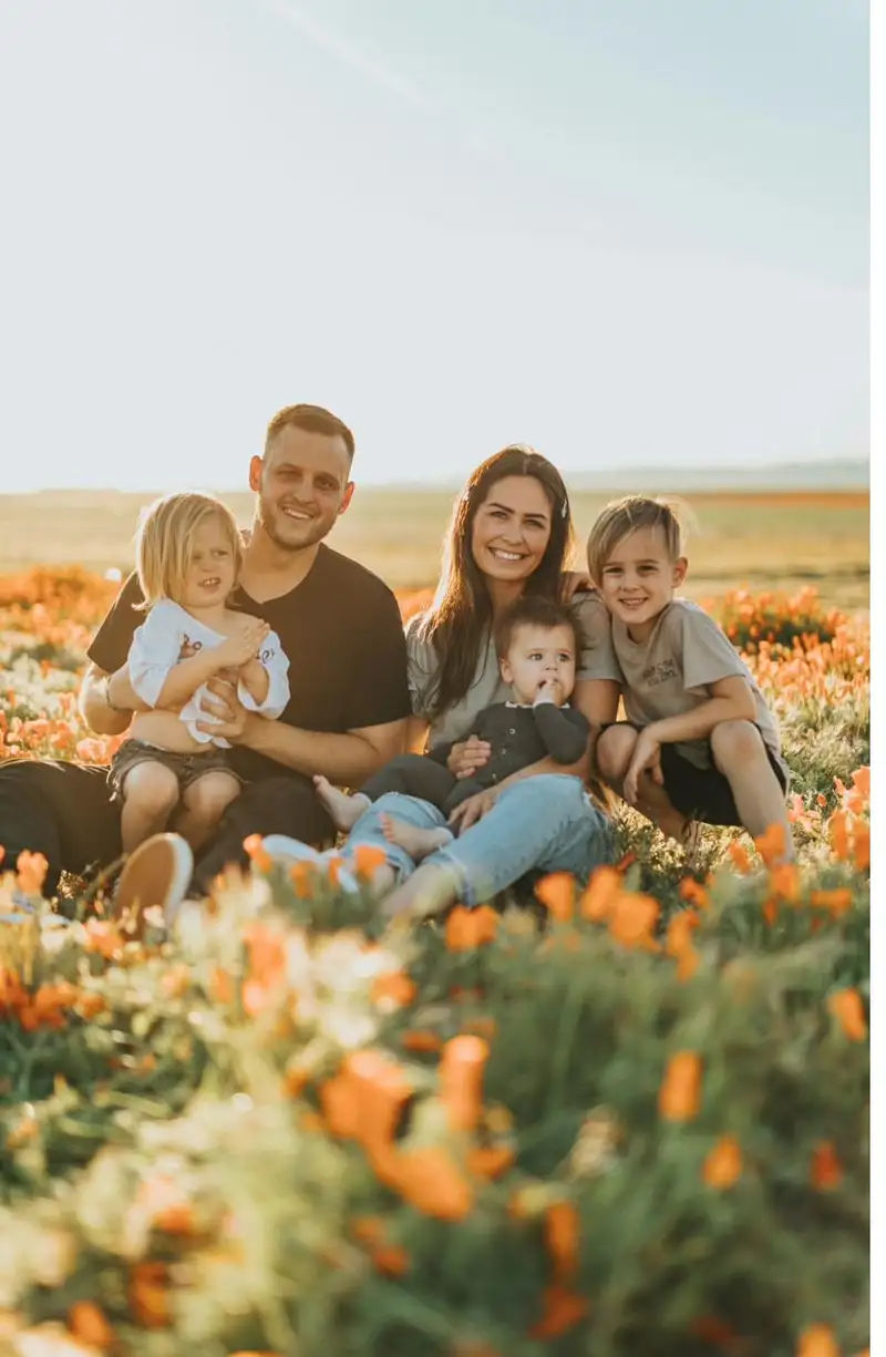 Parents and three children together outdoors at sunset.