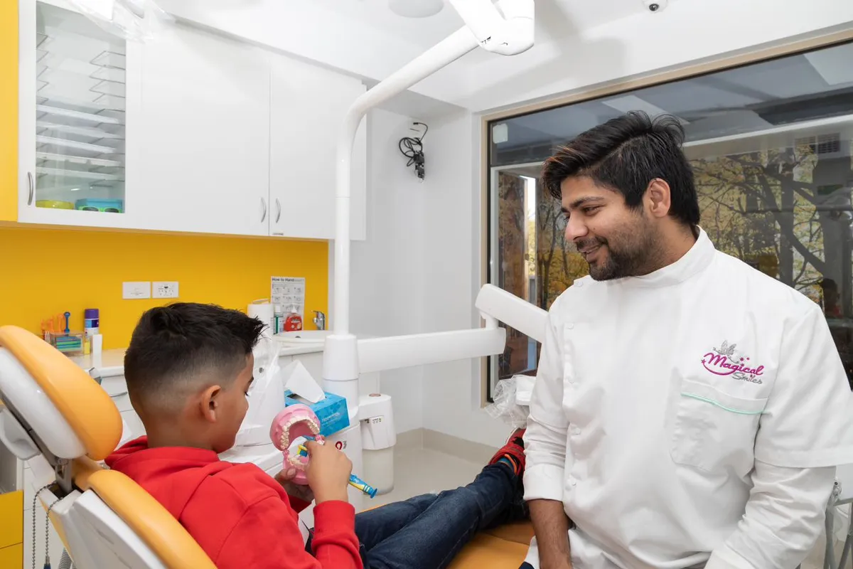 A clinician at a Magical Smiles clinic using a dental model to show a young patient how the teeth and jaw work.