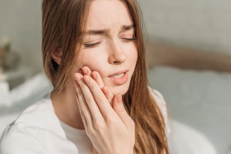 Woman holding her cheek because of tooth pain