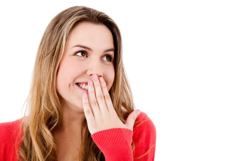 Woman in red laughing with her hand near her mouth