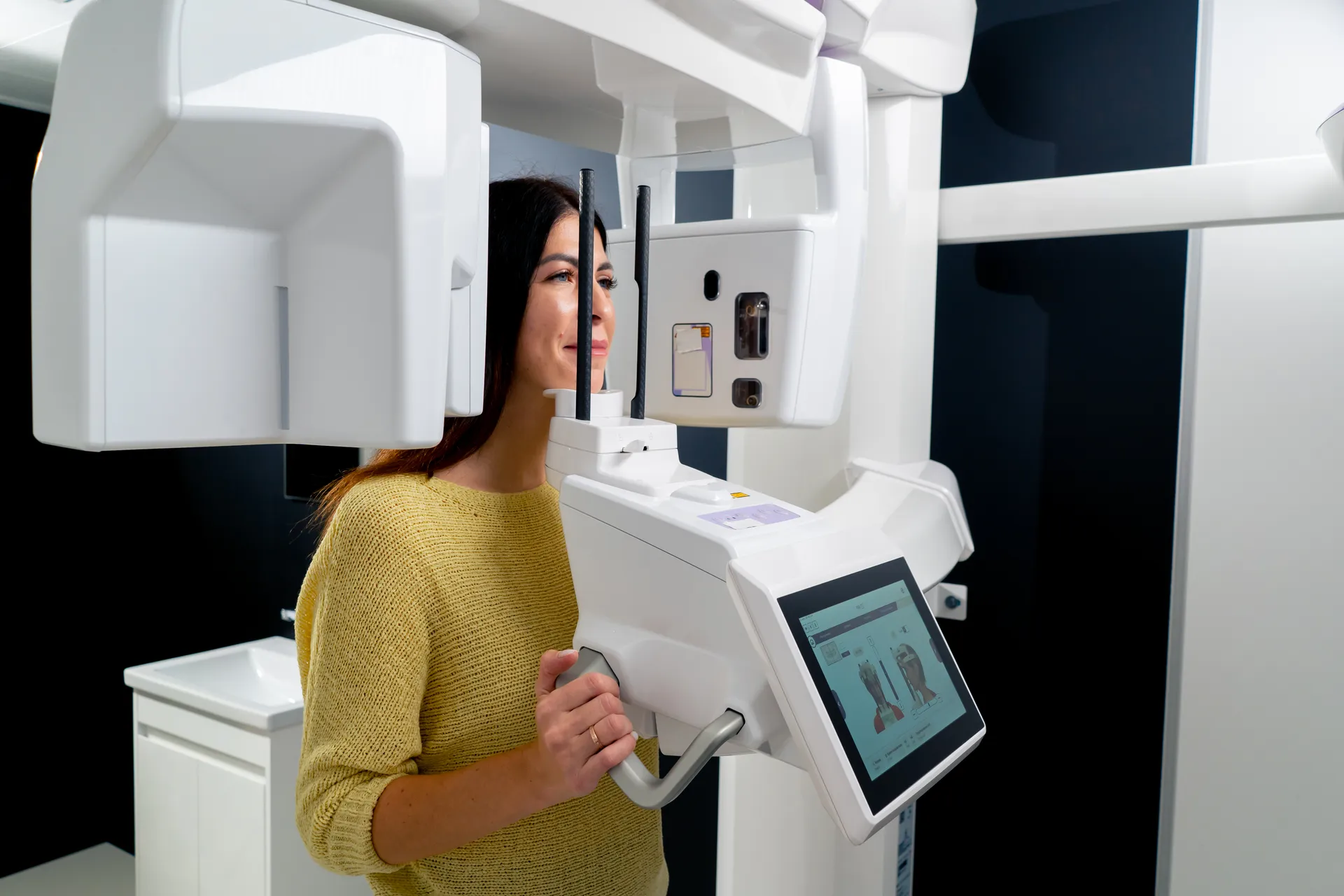 A woman standing in a dental X-ray imaging unit