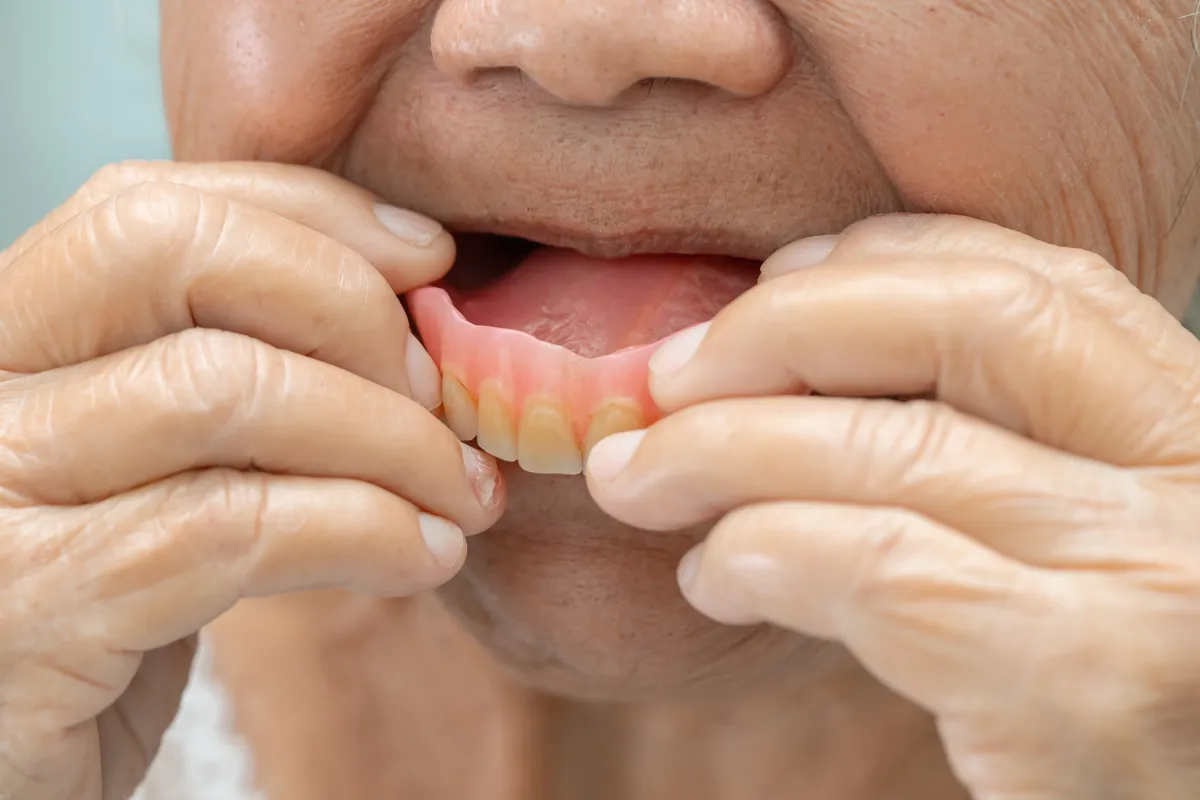 Older patient holding an immediate denture before it is fitted