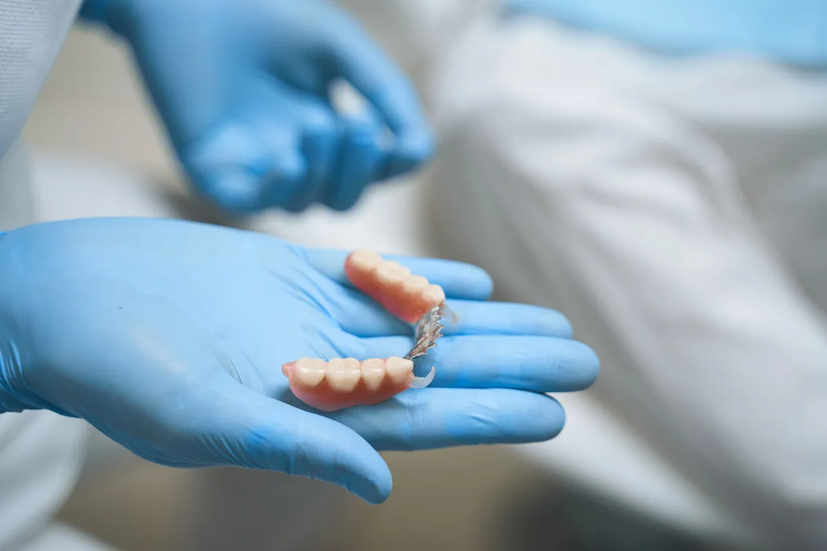Dentist wearing blue gloves holding a partial denture