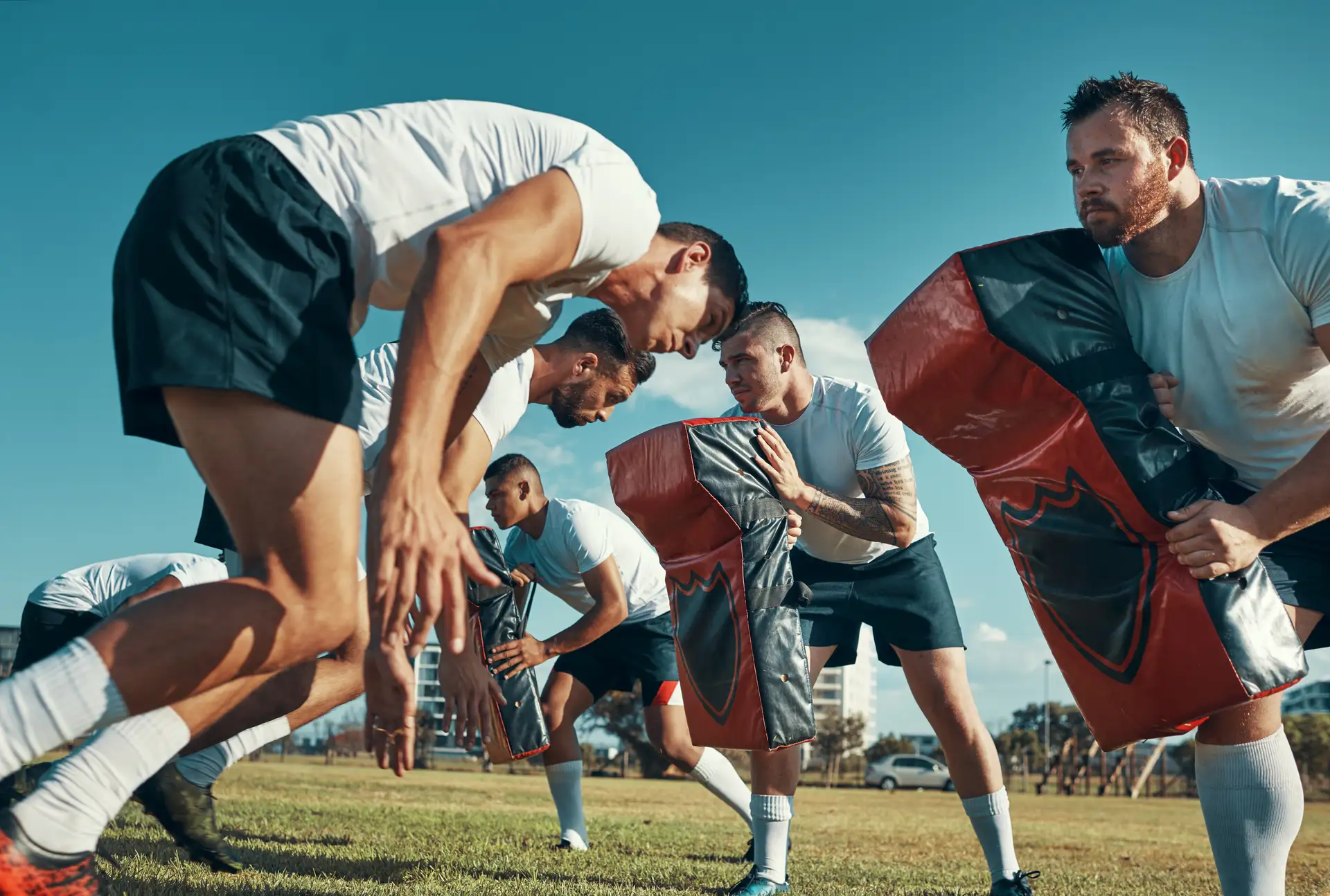 Rugby players practising tackles with pads at an outdoor training session