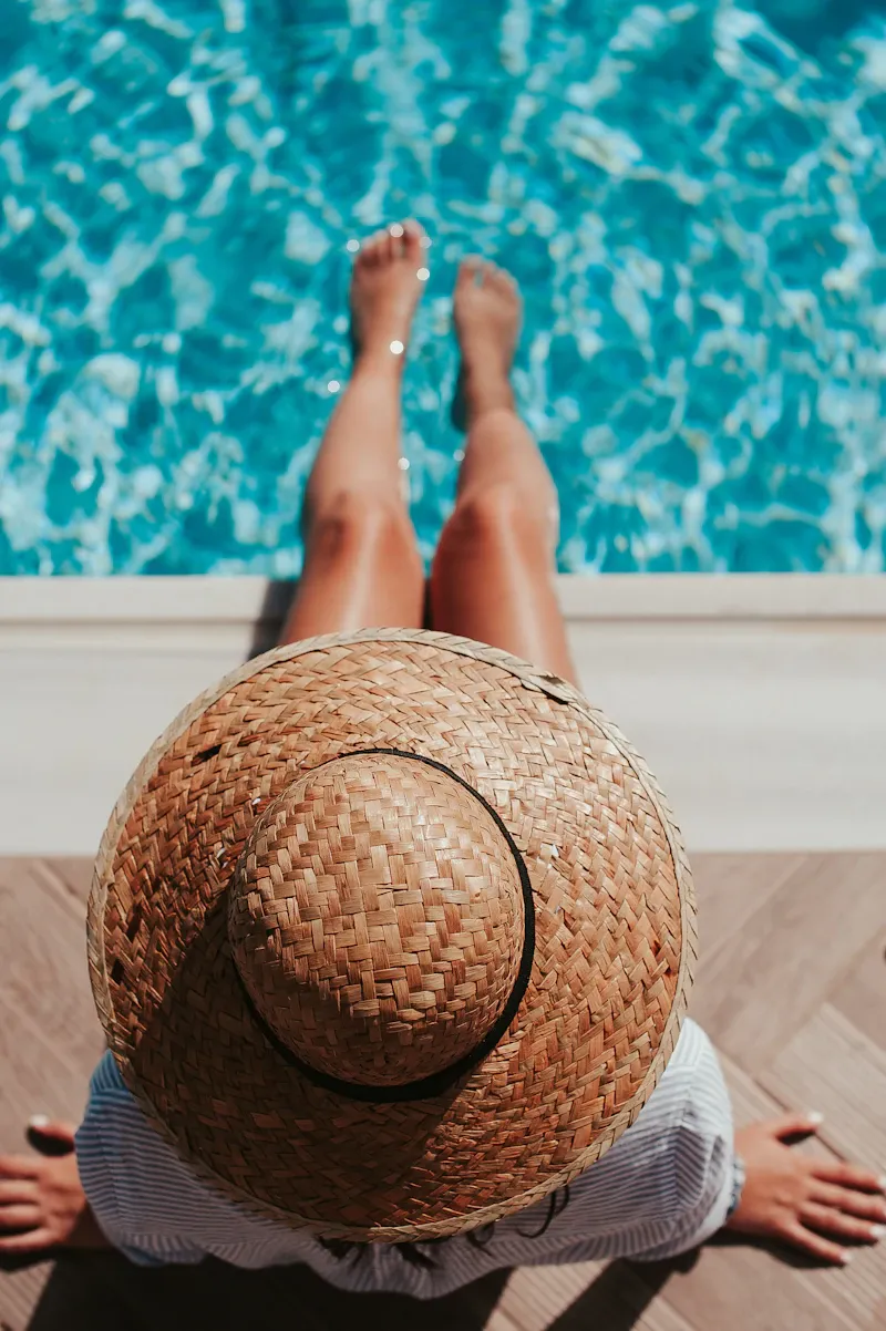 Person sitting on the edge of a pool with their feet in the water