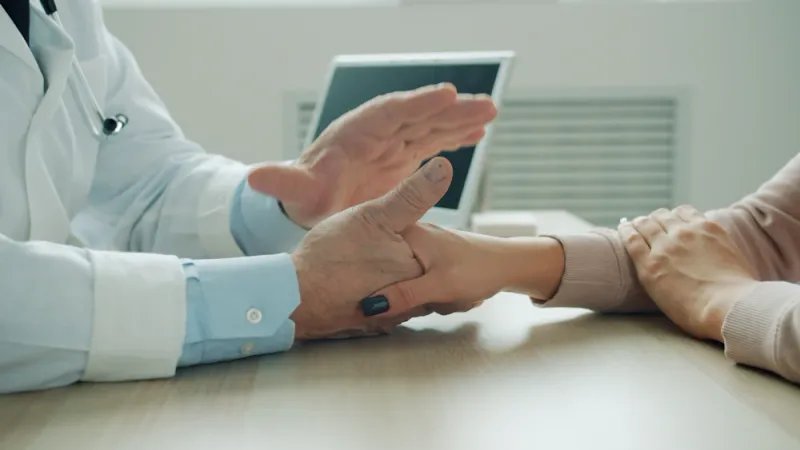 Clinician resting a reassuring hand on a patient's arm while they talk