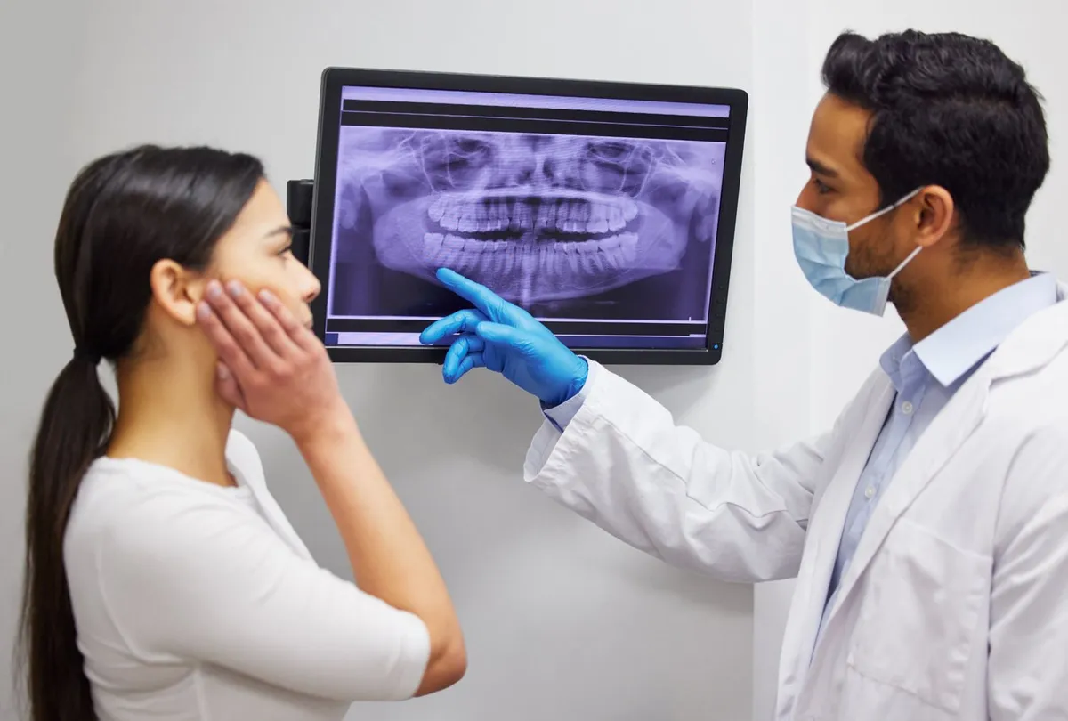 Dentist pointing to the wisdom teeth on a patient's panoramic X-ray