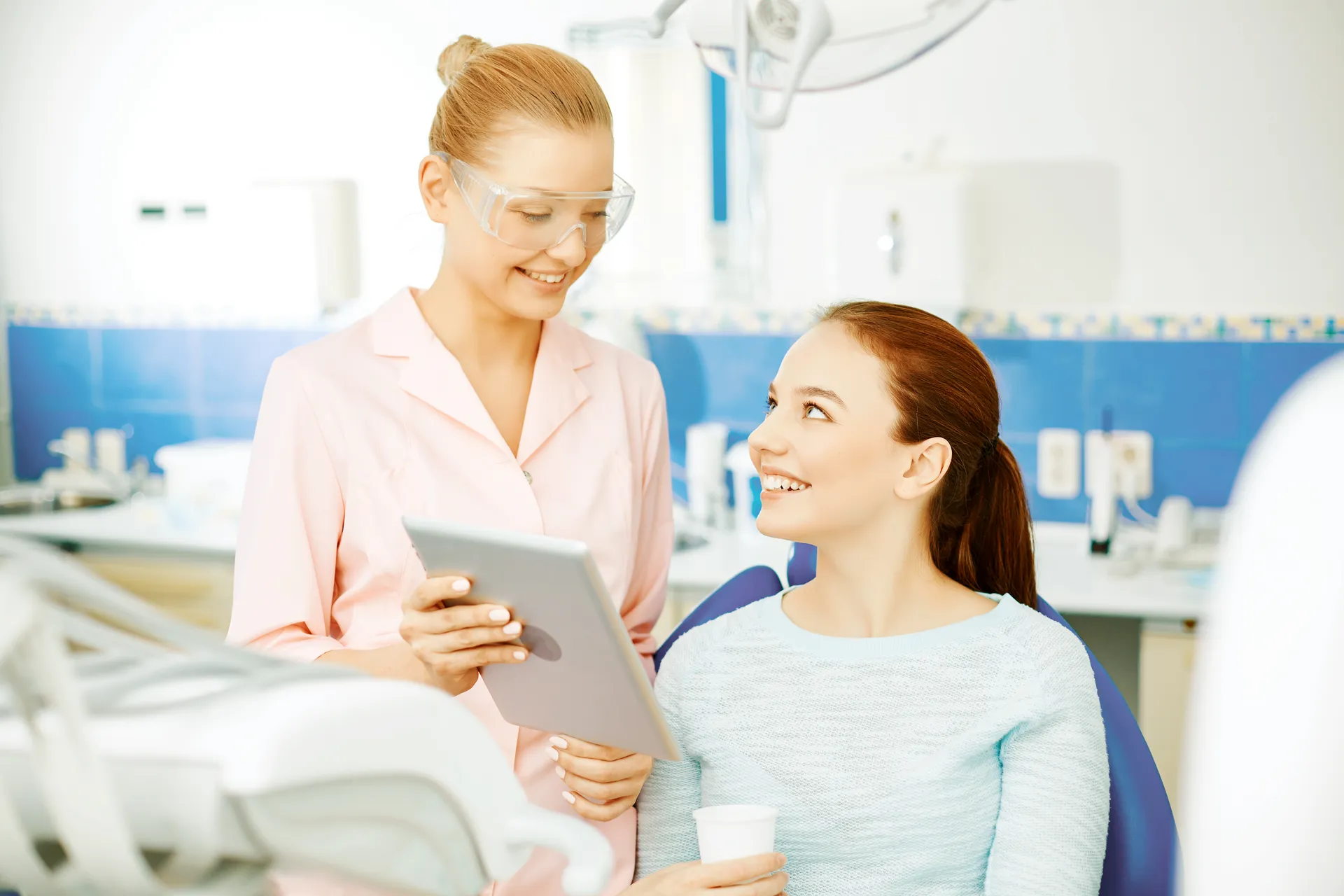 Dentist showing a smiling patient her treatment plan on a tablet