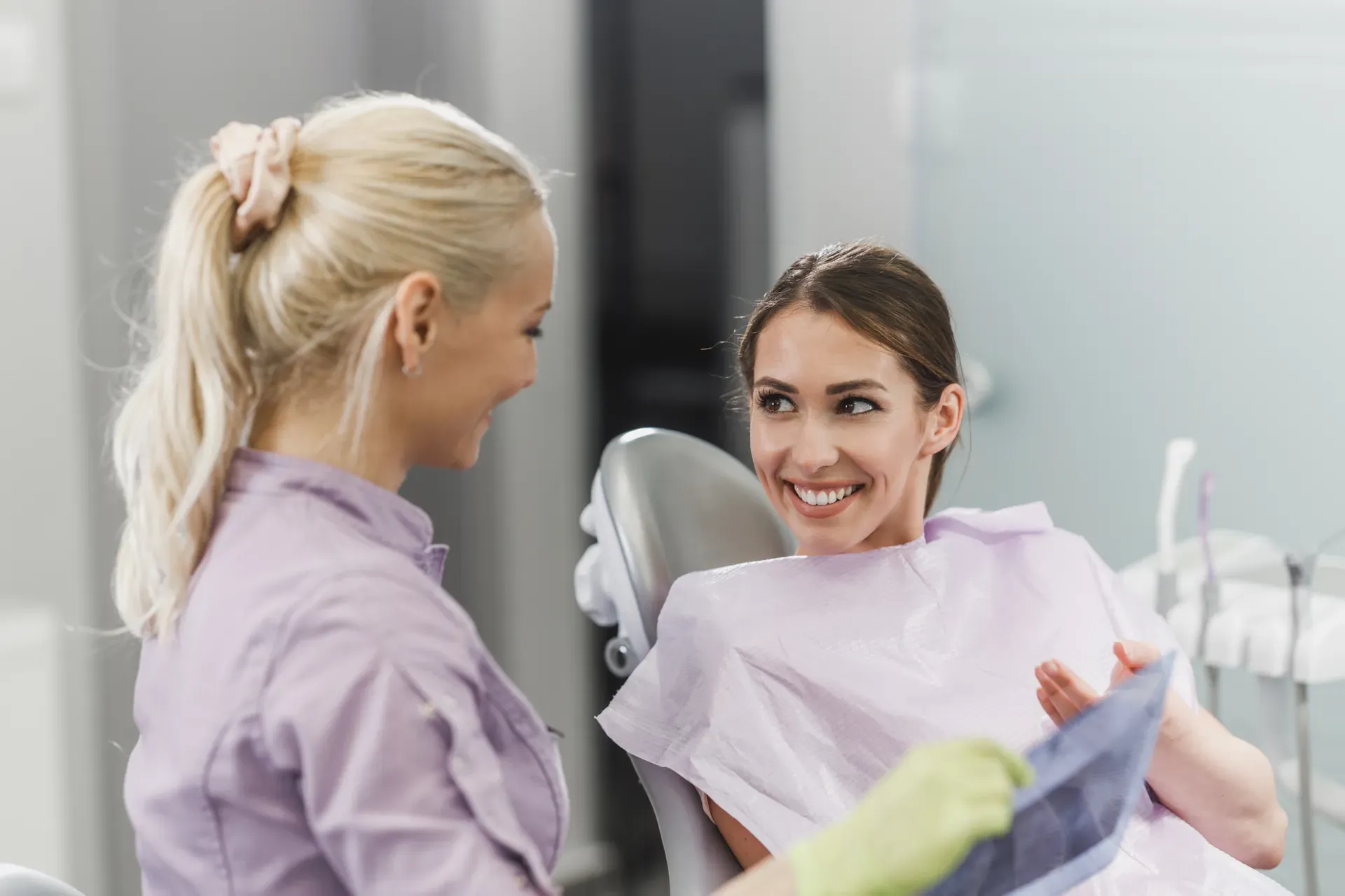 A relaxed, smiling patient chatting with her dentist in the chair