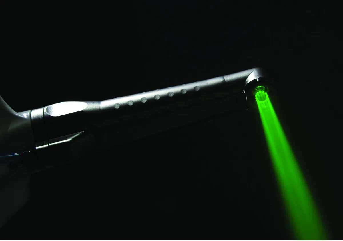 A green guide light shining from the tip of a dental laser handpiece