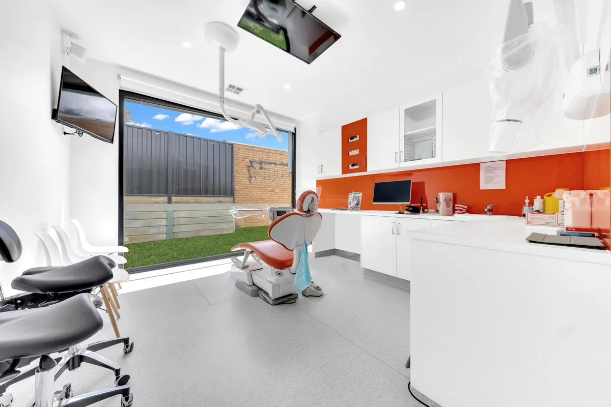 A bright white treatment room with a reclined dental chair