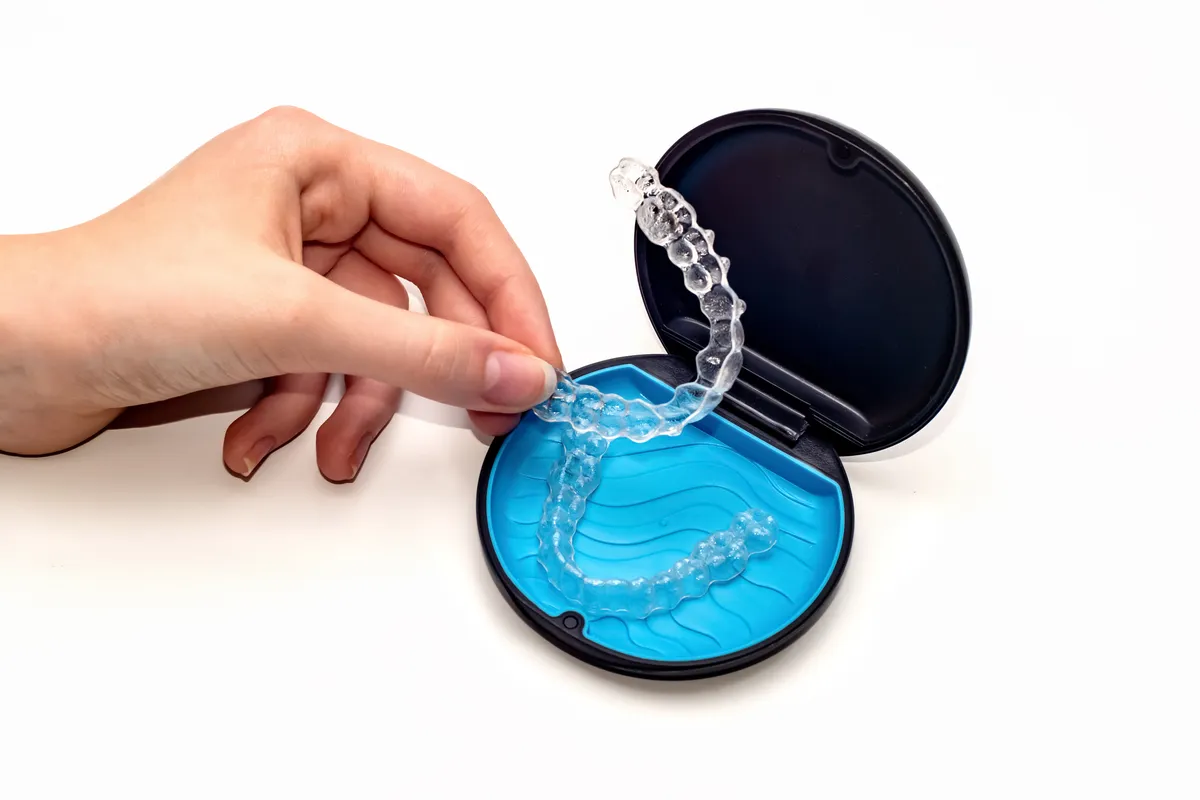 Clear aligner tray sitting next to its travel case