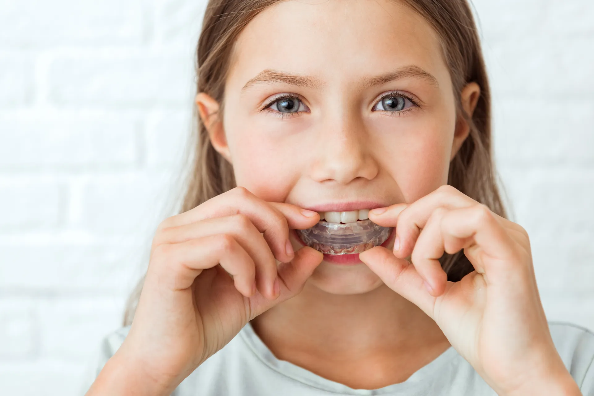 Young girl holding a clear removable dental appliance